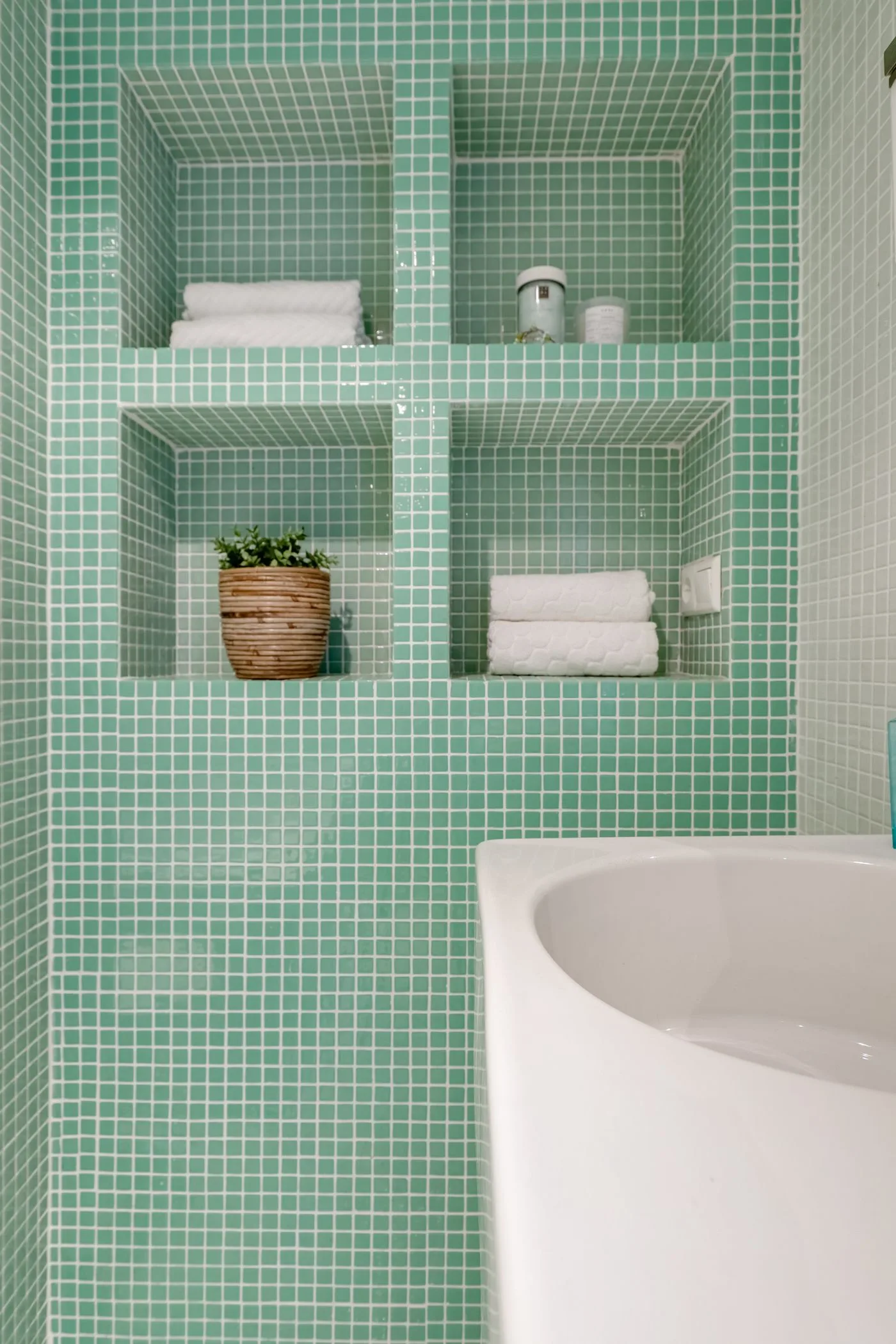Salle de bain avec carrelage vert et étagères
